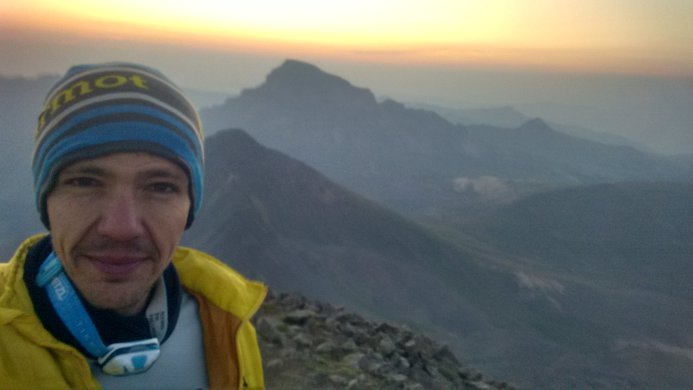 A selfie of a hiker atop Wetterhorn Peak with Uncompahgre Peak behind him