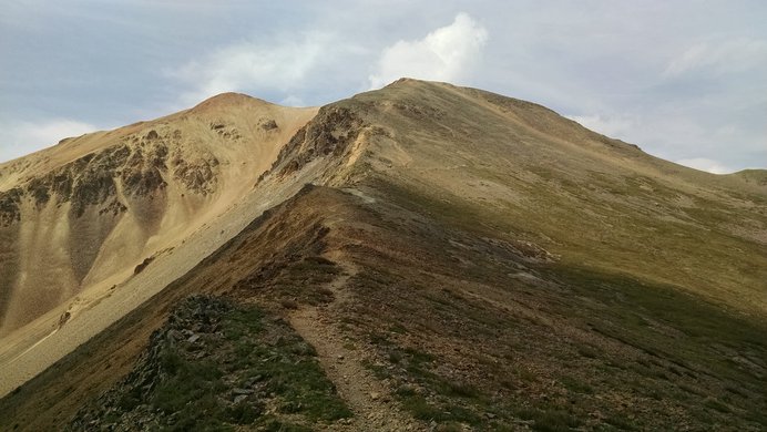 The rocky red summit of Redcloud Peak contrasts with its green basin below