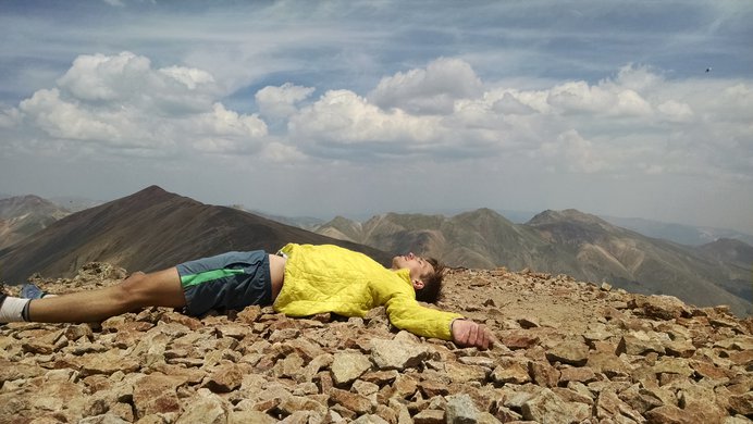 A tired hiker lies down on Sunshine Peak's summit