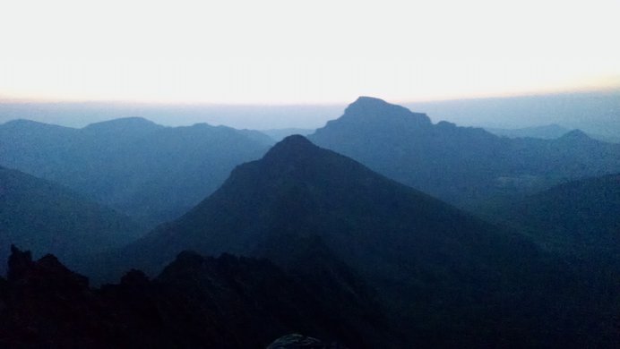 A hazy blue early-morning view of Matterhorn Peak and Uncompahgre Peak seen from the flank of Wetterhorn Peak