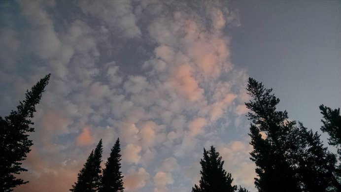 The orange glint of sunrise on clouds above the Devils Thumb Trail.